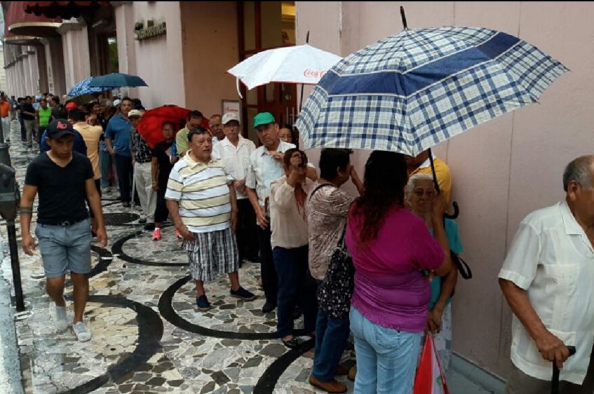 Larga fila para retiro de pensiones, jubilados deben esperar bajo la lluvia