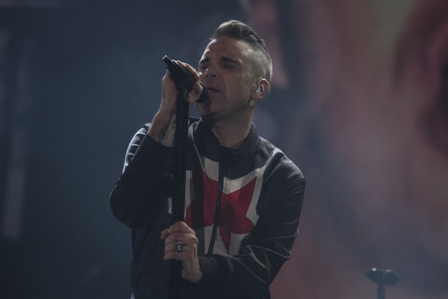 Robbie Williams rinde homenaje a su padre y llena al público de sorpresas