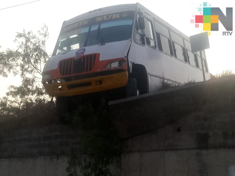 Camión del transporte público a punto de caer de muro de contención