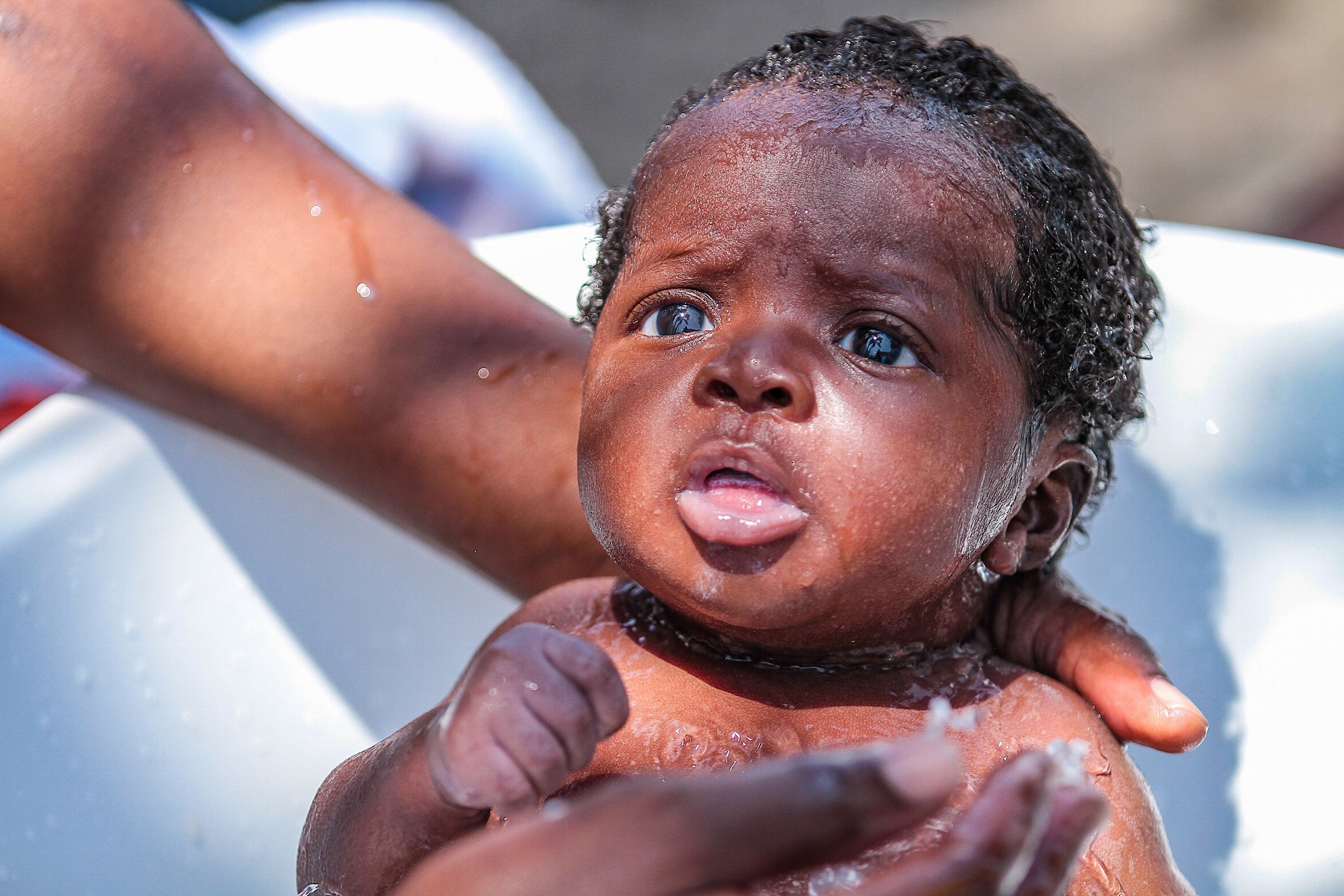 Niño de origen africano recibe baño en campamento de migrantes