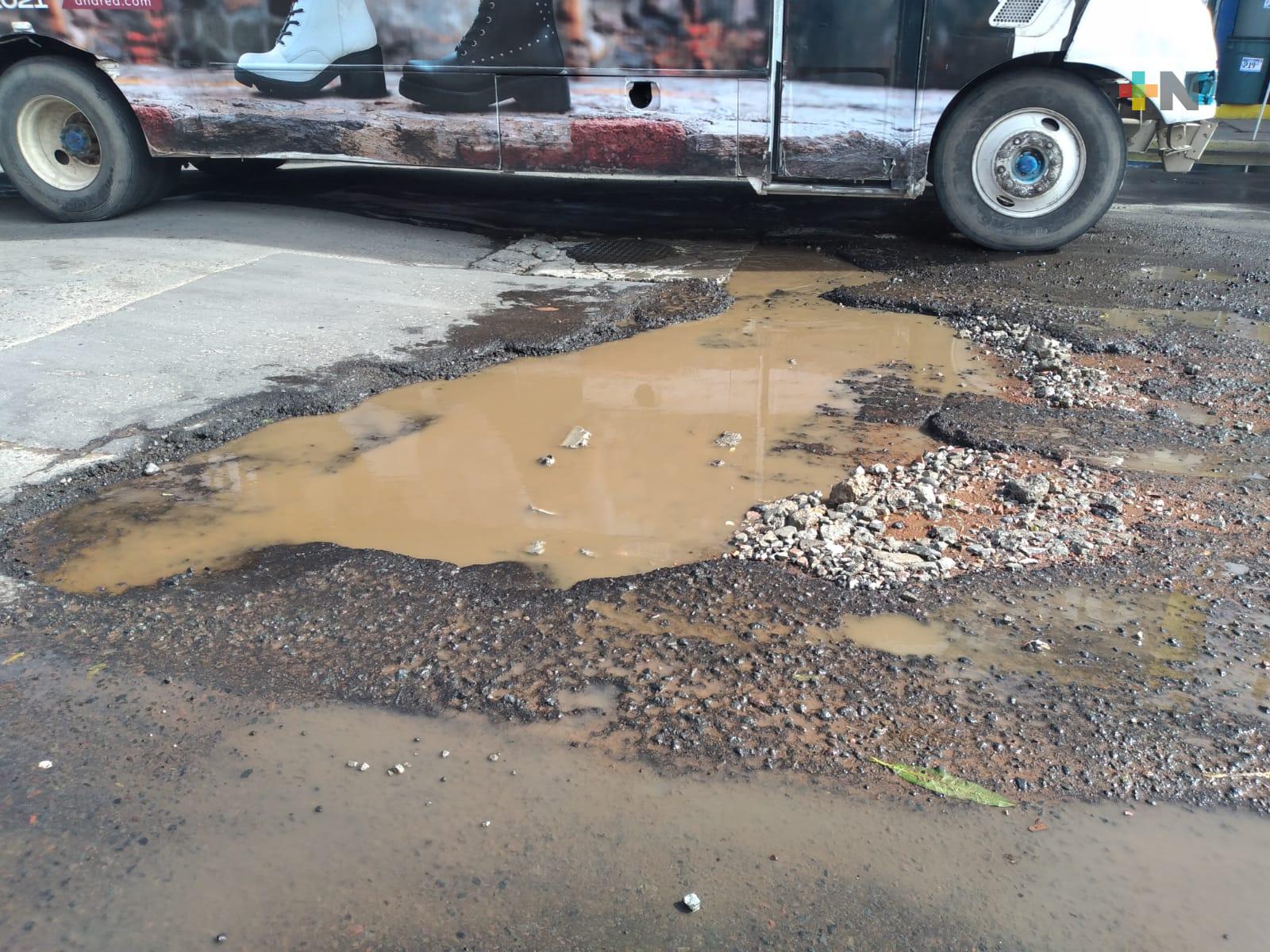 Automovilistas lidian con baches y agua estancada en esta calle de Veracruz